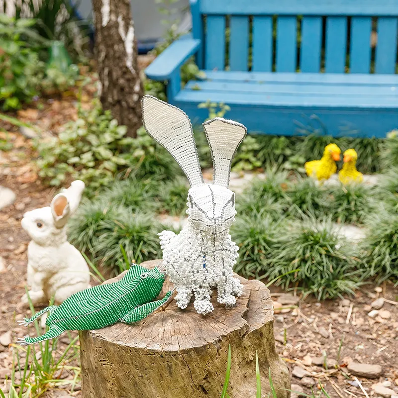 The Bunny Hutch is one of the most loved spaces in the Bluebird Garden. Children delight in caring for the bunnies, observing their behaviour, and learning about gentleness, responsibility, and respect for animals through daily interaction. A decorative beaded rabbit and other animal figures sit among plants and garden features in a peaceful outdoor space, creating a whimsical environment that encourages curiosity, observation, and imaginative play.